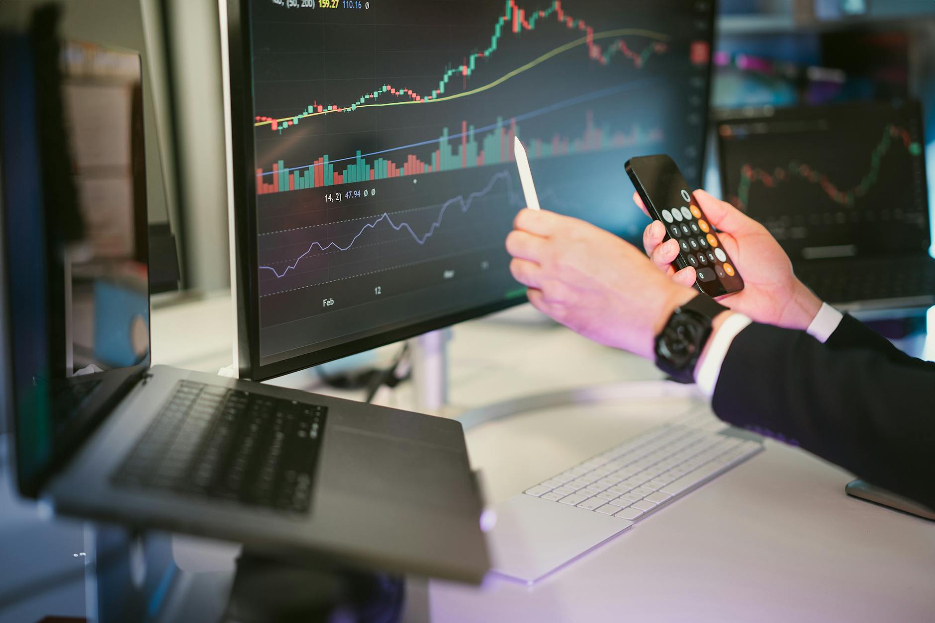 Ilustrasi: A professional analyzing financial charts on computer monitors and a smartphone, symbolizing digital finance strategies.