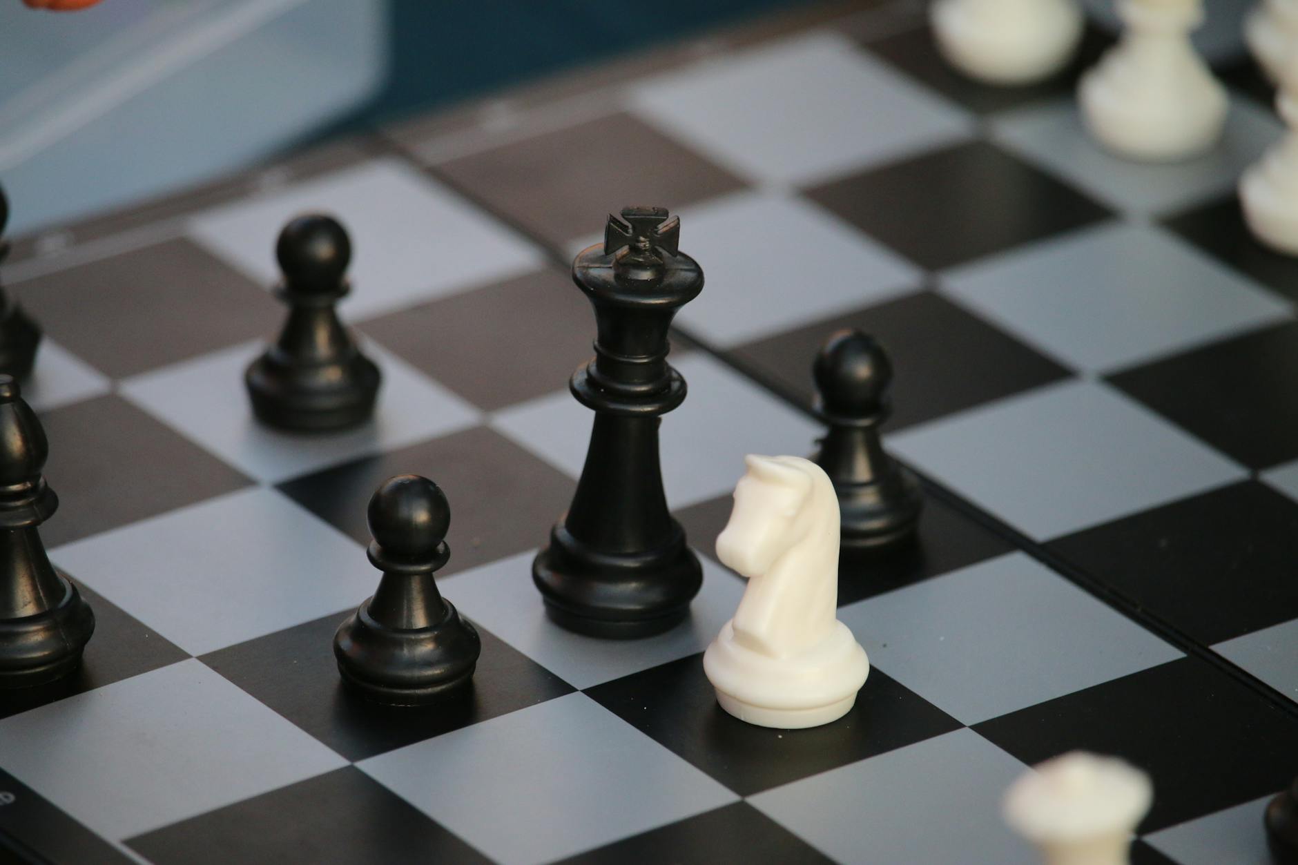 Ilustrasi: Close-up of a chessboard with black and white pieces in strategic positions.