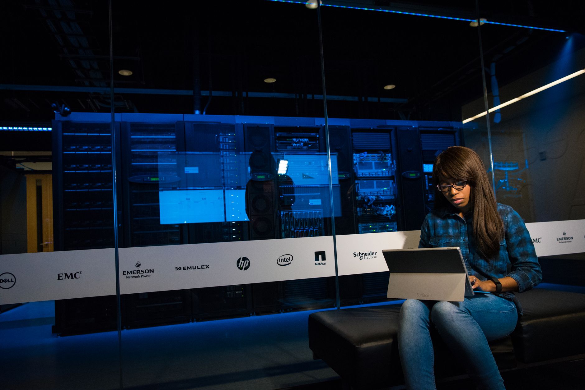 Ilustrasi: Woman using a laptop in a server room, showcasing modern technology and work environment.