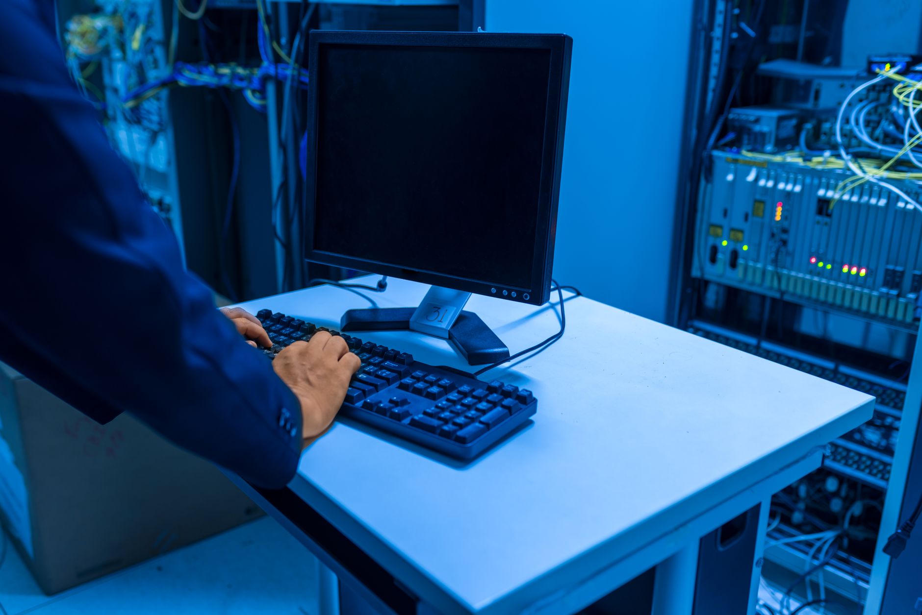 Ilustrasi: An IT professional operates a computer in a server room, managing network systems and connected devices.