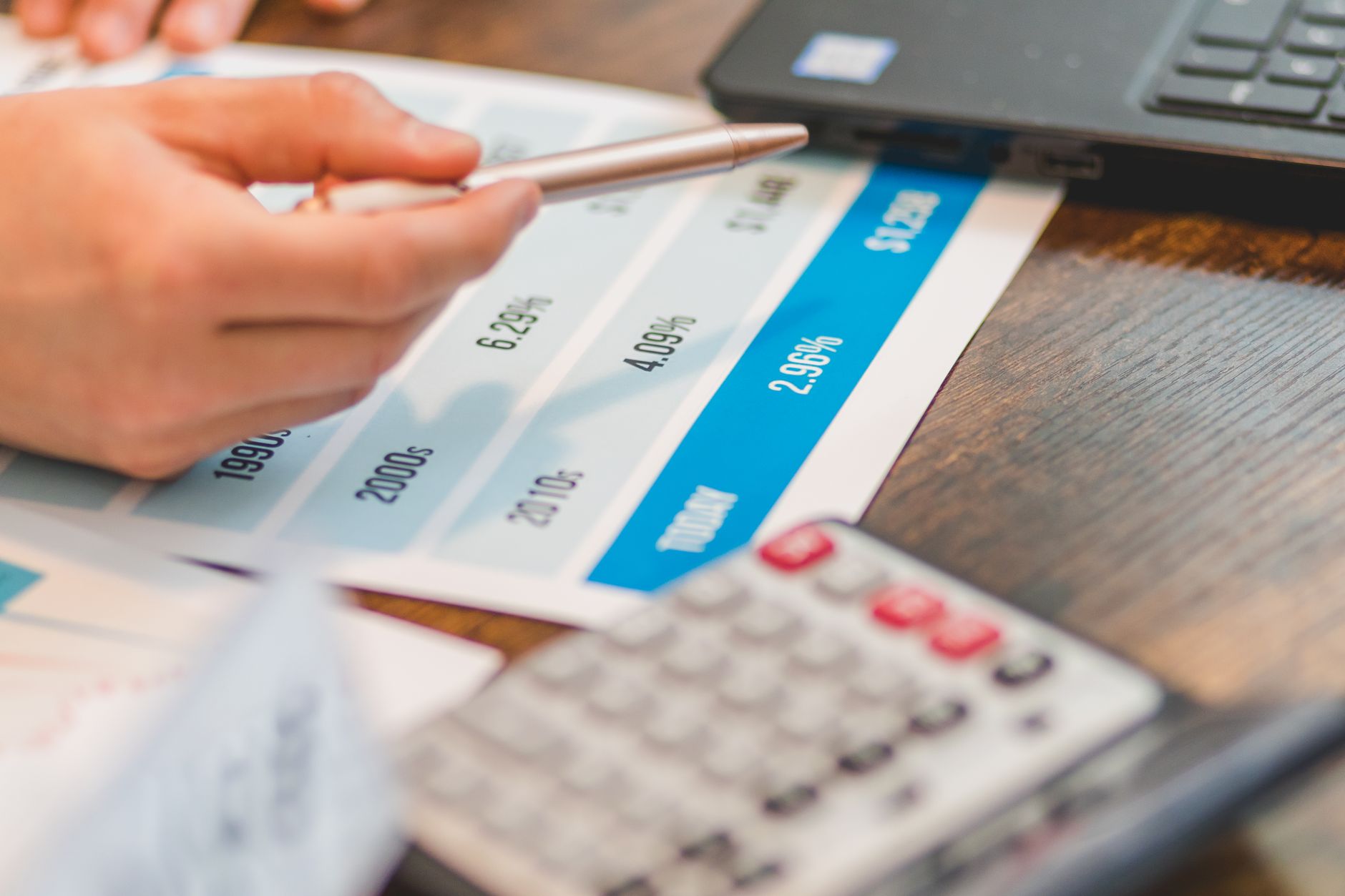 Ilustrasi: Close-up of a hand using a ballpen and calculator to analyze interest rates on a chart.